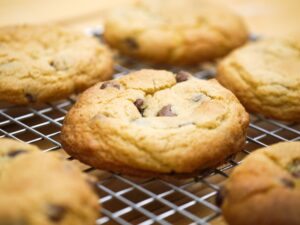 Close-up of freshly baked chocolate chip cookies cooling on a wire rack, showcasing delicious homemade treats.