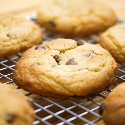 Close-up of freshly baked chocolate chip cookies cooling on a wire rack, showcasing delicious homemade treats.