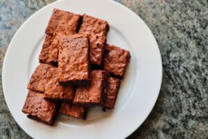 A top view of freshly baked, delicious chocolate brownies served on a white ceramic plate.